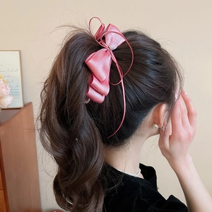 Detail of pink satin bow hair clip with zircon star on dark ponytail for elegant look