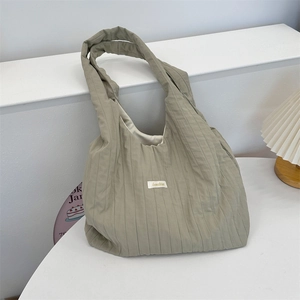 Detail shot of the sage green pleated shoulder bag featuring a white woven brand label