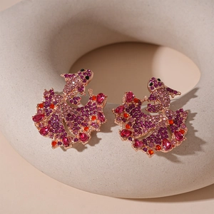 Macro detail of koi fish earrings featuring purple pave crystals and red teardrop stones
