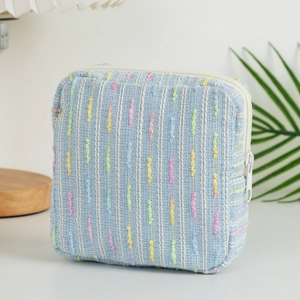 Detailed view of the woven textured light blue striped makeup bag with white zipper
