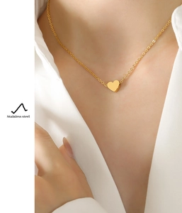 Close-up of heart pendant necklace in gold stainless steel worn by a model