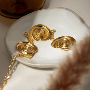 Elegant 18k gold plated stainless steel triple spiral shell pendant necklace in a ceramic tray