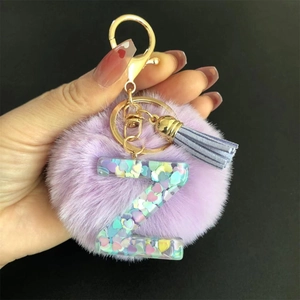 Détail d'un porte-clés pompon violet avec pendentif lettre Z en résine et pompon doré