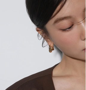 Close-up of model wearing gold irregular lava earrings with minimalist twisted metal texture