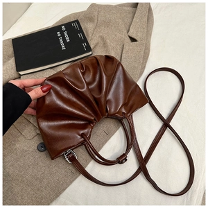 Detail of deep brown pleated cloud bag with soft leather texture and slim strap
