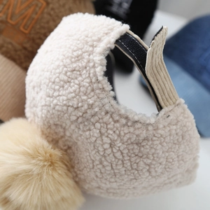 Detailed close-up of teddy fleece baseball cap with a corduroy strap and large pom-pom