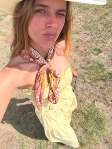 Detail of smocked A-line dress with ethnic scarf and summer straw hat on grass
