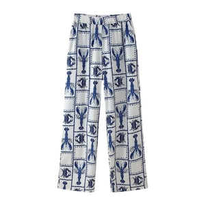 Detailed flat lay of white wide-leg trousers with blue lobster and crab patterns