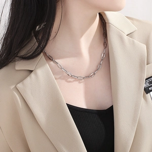 Close-up of a silver geometric interlocking chain necklace worn with a stylish blazer