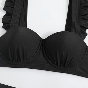 Detail of black bikini top with ruffled shoulder straps and ruched underwire cups