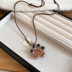 Macro detail of leopard print paw pendant with silver trim on a brown cord necklace