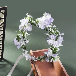 Detailed view of floral bridal crown with purple and white fabric petals on a wooden box