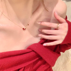 Close-up of gold butterfly necklace and sparkling diamond ring set on a red knit sweater