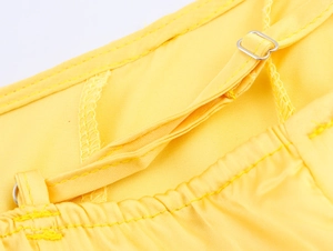 Detail of adjustable metal buckle on yellow satin dress thin shoulder strap with stitching