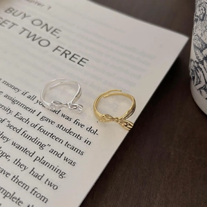 Detailed shot of gold and silver bow rings with textured finish on open book pages
