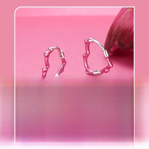 Macro shot of silver heart hoop earrings with rose pink enamel finish and polished luster