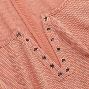 Dettaglio dell'abito in maglia rosa salmone con occhielli in metallo e zip piatta