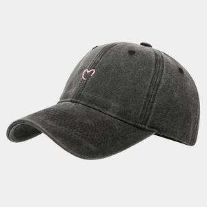 Detail einer dunkel gewaschenen Denim-Basecap mit rosa Herz-Stickerei auf der Vorderseite