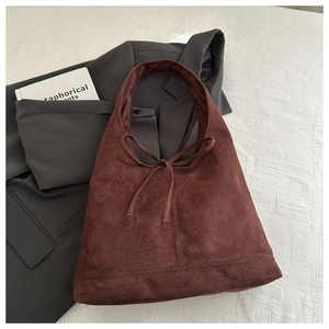 Detail of a brown faux suede tote bag with soft texture and decorative ties for women