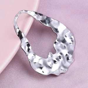 Macro shot of silver hammer texture open pendant on soft pink fabric background