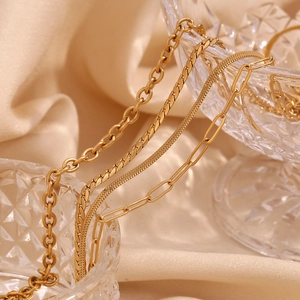 Detail of four distinct 18K gold plated stainless steel chains on glass edge