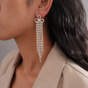 Détail de boucles d'oreilles nœud argenté avec pampilles en strass sur un modèle