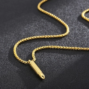 Macro detail of a golden bullet-shaped pendant on a titanium steel necklace chain