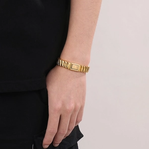 Detail of gold-plated stainless steel watchband-style link bracelet on male wrist