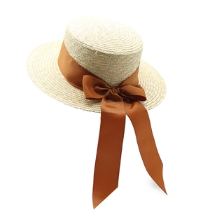 Détails du tissage d'un chapeau de paille ivoire avec un grand ruban marron élégant
