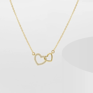 Close-up of golden interlocking heart pendant with sparkling cubic zirconia inlay