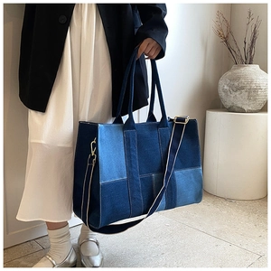 Detail of color-block denim tote bag featuring adjustable strap and metallic buckles