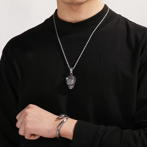 Close-up of silver steel leopard head necklace and open bracelet set on model
