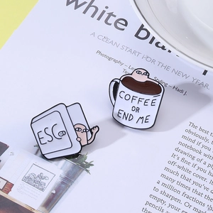 Detail view of coffee cup and ESC key enamel pins on a lifestyle magazine background