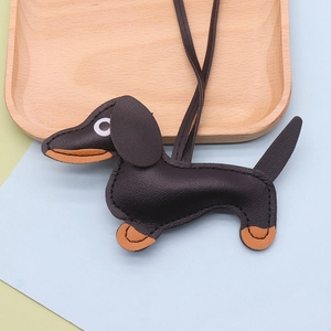 Close-up of black and brown leather dachshund bag charm on a light wooden tray