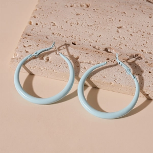 Close-up of light blue geometric hoop earrings resting on a beige textured stone base