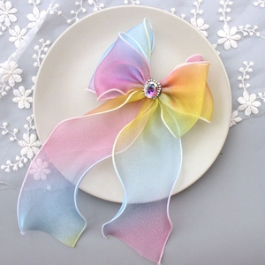 Close-up of rainbow gradient tulle hair bow with sparkling rhinestone on white lace