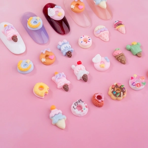 Colorful resin donut and ice cream nail art charms arranged on a pink background