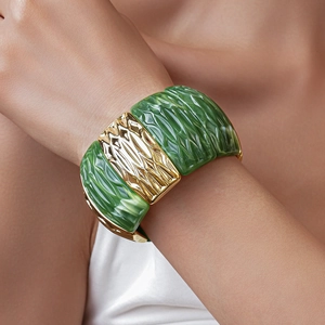 Close-up of green textured acrylic segments and golden metal links on a wide stretch bracelet
