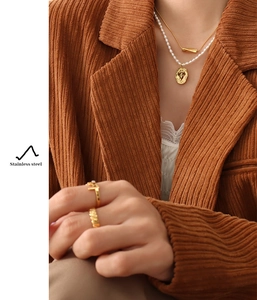 Detail of layered gold-plated stainless steel necklace and pearl strand on model