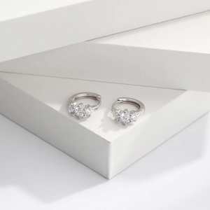 Close-up of S925 sterling silver hoop earrings with three clear zircon stones on a white block