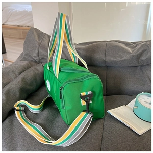 Detail view of a green cylinder sports bag with colorful stripes on a grey sofa