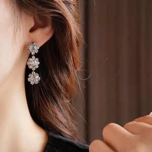 Close-up of silver-tone sunflower drop earrings with sparkling crystals on model