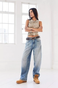 Close-up of vintage washed loose wide-leg jeans styled with brown leather belt and boots