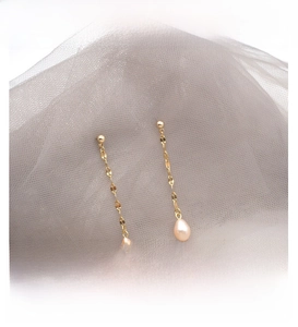 Detail of long tassel earrings featuring freshwater pearls and delicate gold chains
