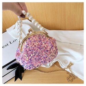 Detail of pink sequin shell bag featuring a pearl handle and gold metal clasp