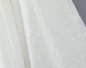 Détail de l'exquise broderie florale blanche sur un tissu de dentelle haut de gamme