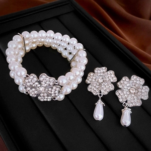Macro shot of three-row pearl bracelet and floral drop earrings with diamond accents