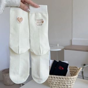Detail of cream white cotton socks featuring heart and Follow your heart embroidery