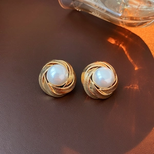 Close-up of vintage gold spiral pearl stud earring on dark leather background