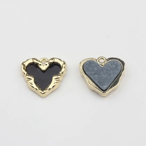 Detail of gold alloy heart charms with black and grey enamel for DIY jewelry making